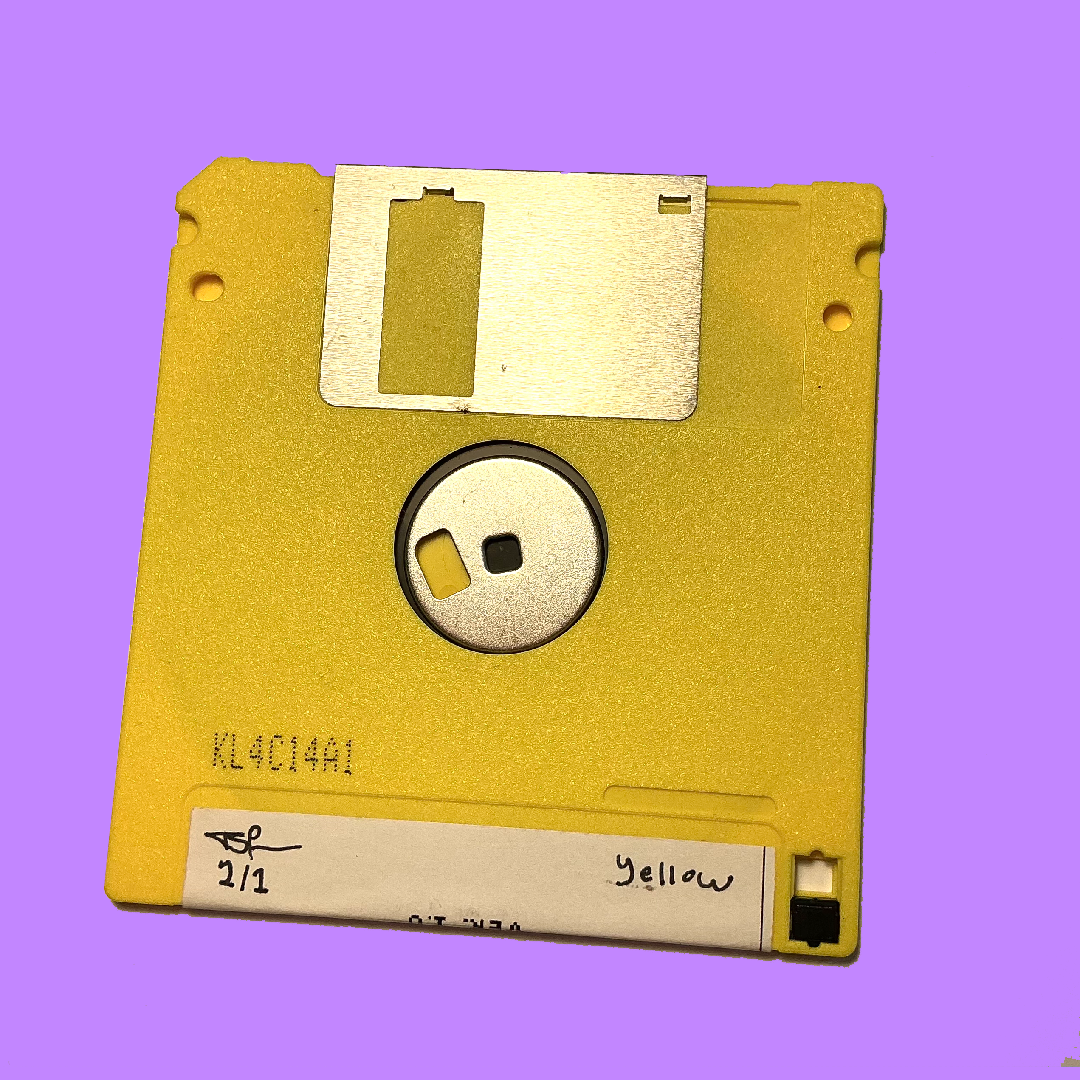 A vintage yellow 3.5-inch floppy diskette with a silver metal shutter and a white paper label, shown against a solid purple background.