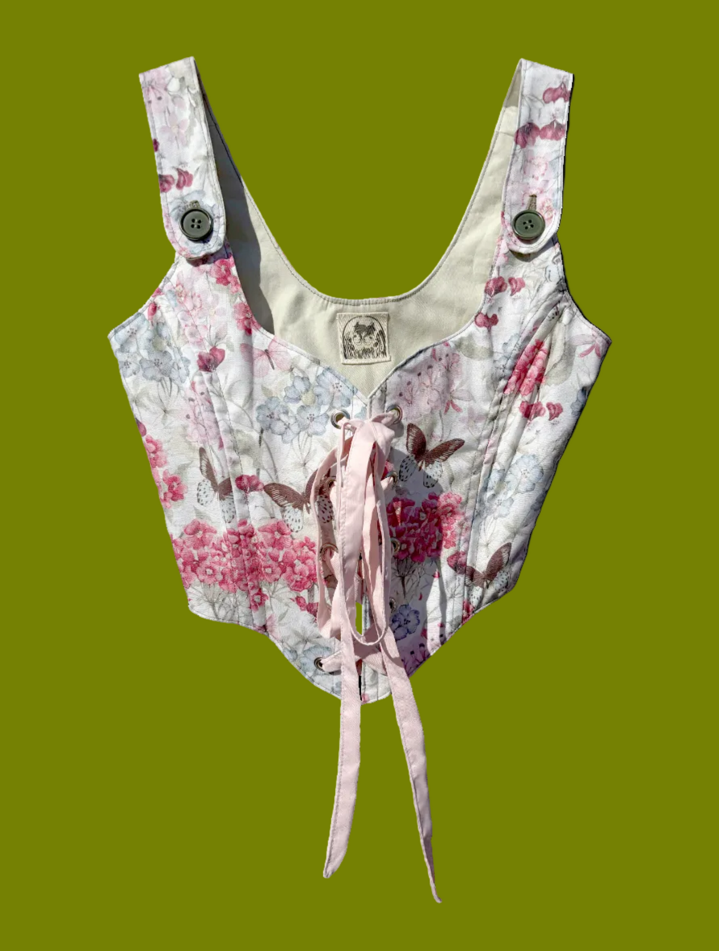 Butterfly and floral printed corset with pink ribbon tying it and olive green buttons on the straps.