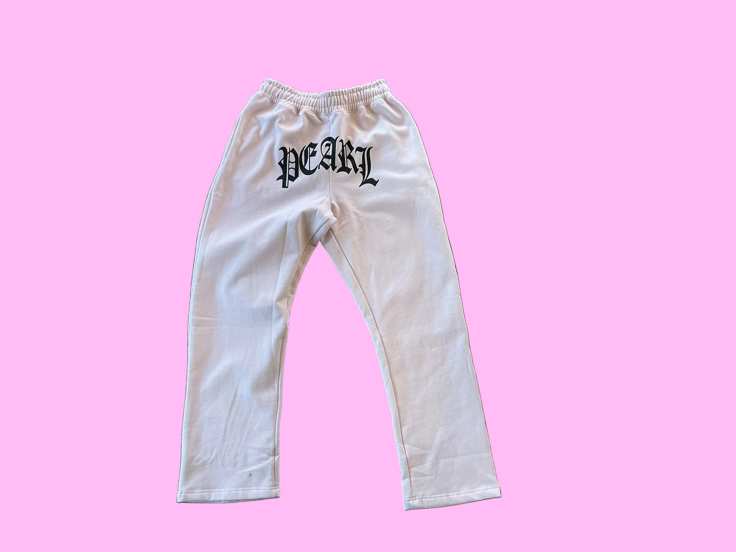 White sweatpants with black text on a textured concrete floor, pearl rachinsky