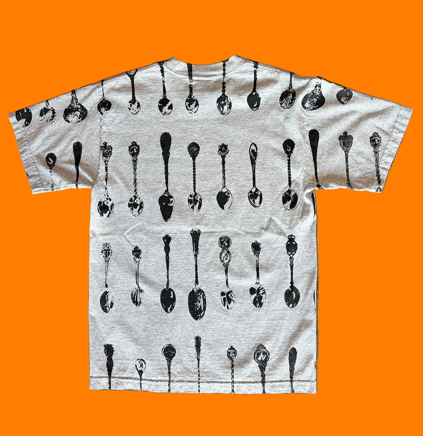 Back of the BY.Everyone heather grey shirt with all-over spoon pattern print in black. 